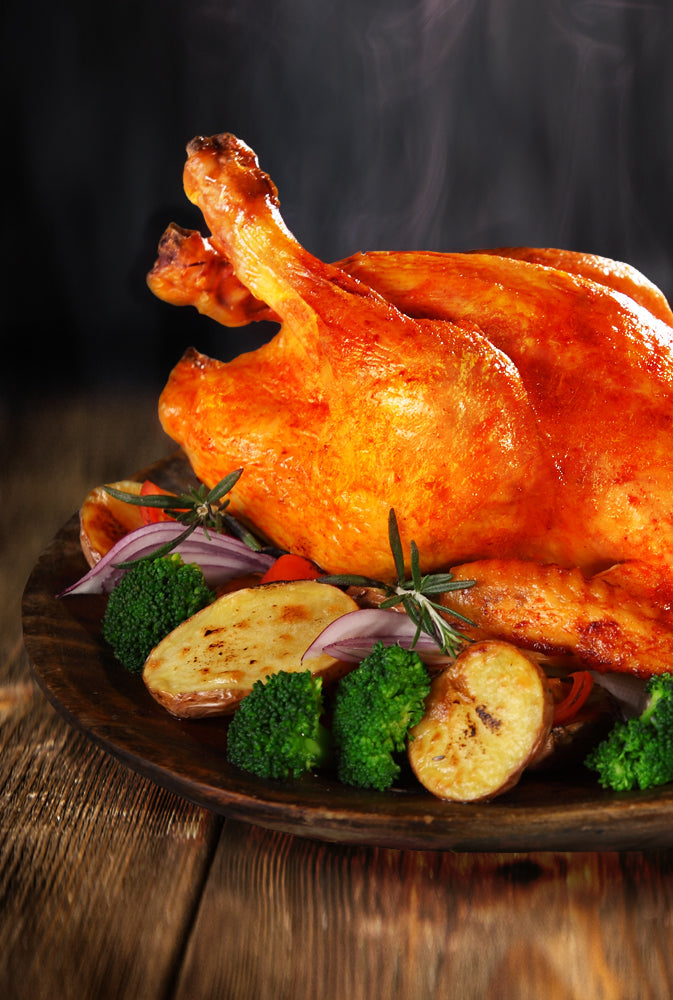 Grillhähnchen mit knuspriger Kruste, appetitlich mit Grillgemüse und Kartoffeln angerichtet auf einem rustikalen Holztisch.