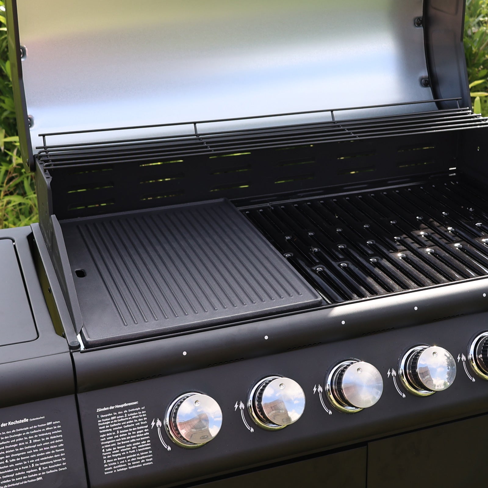 Die TAINO PRO/RED Gusseisen-Grillplatte liegt mit geriffelter Seite nach oben auf einem Gasgrill