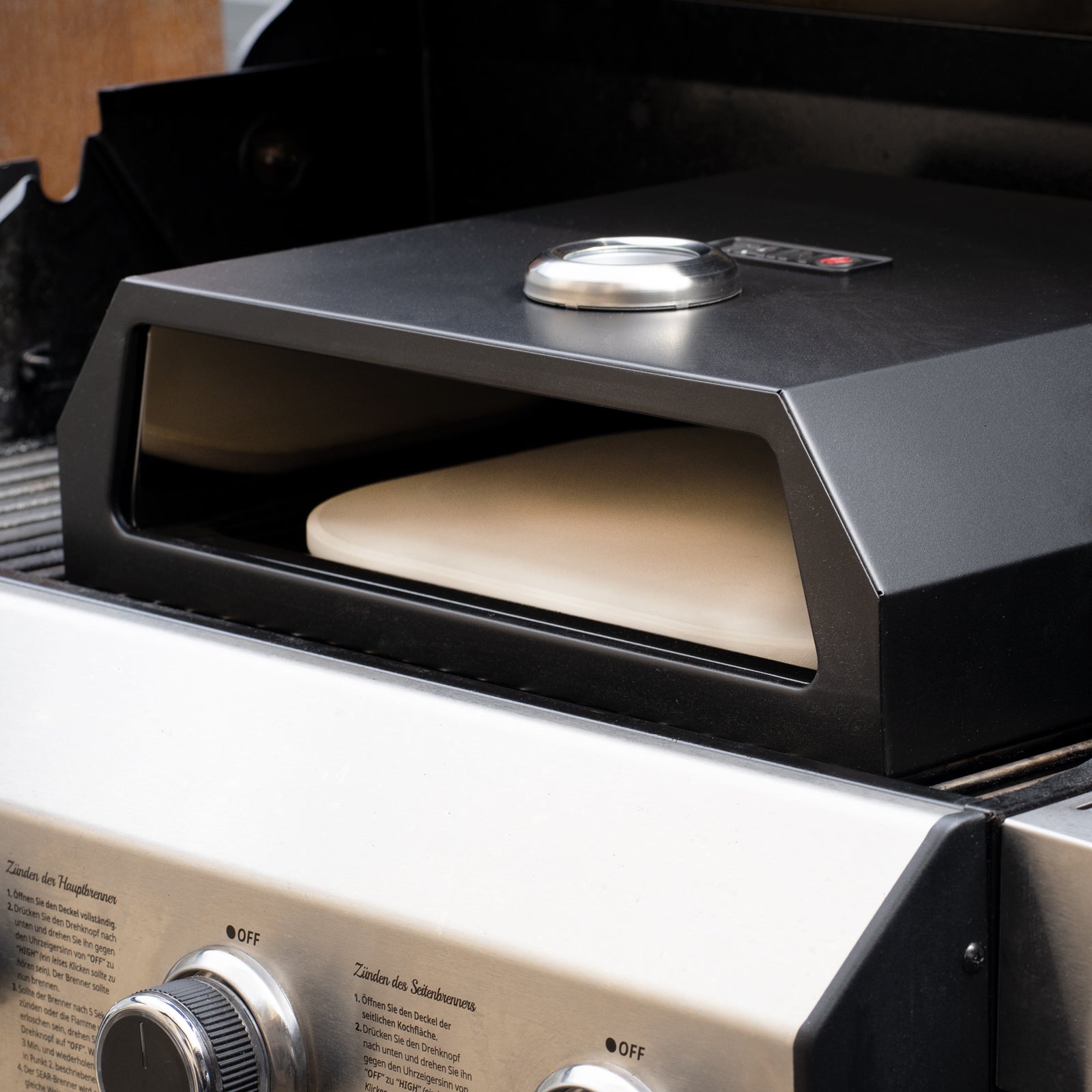schwarze TAINO Pizzabox mit Pizzastein steht auf Gasgrill