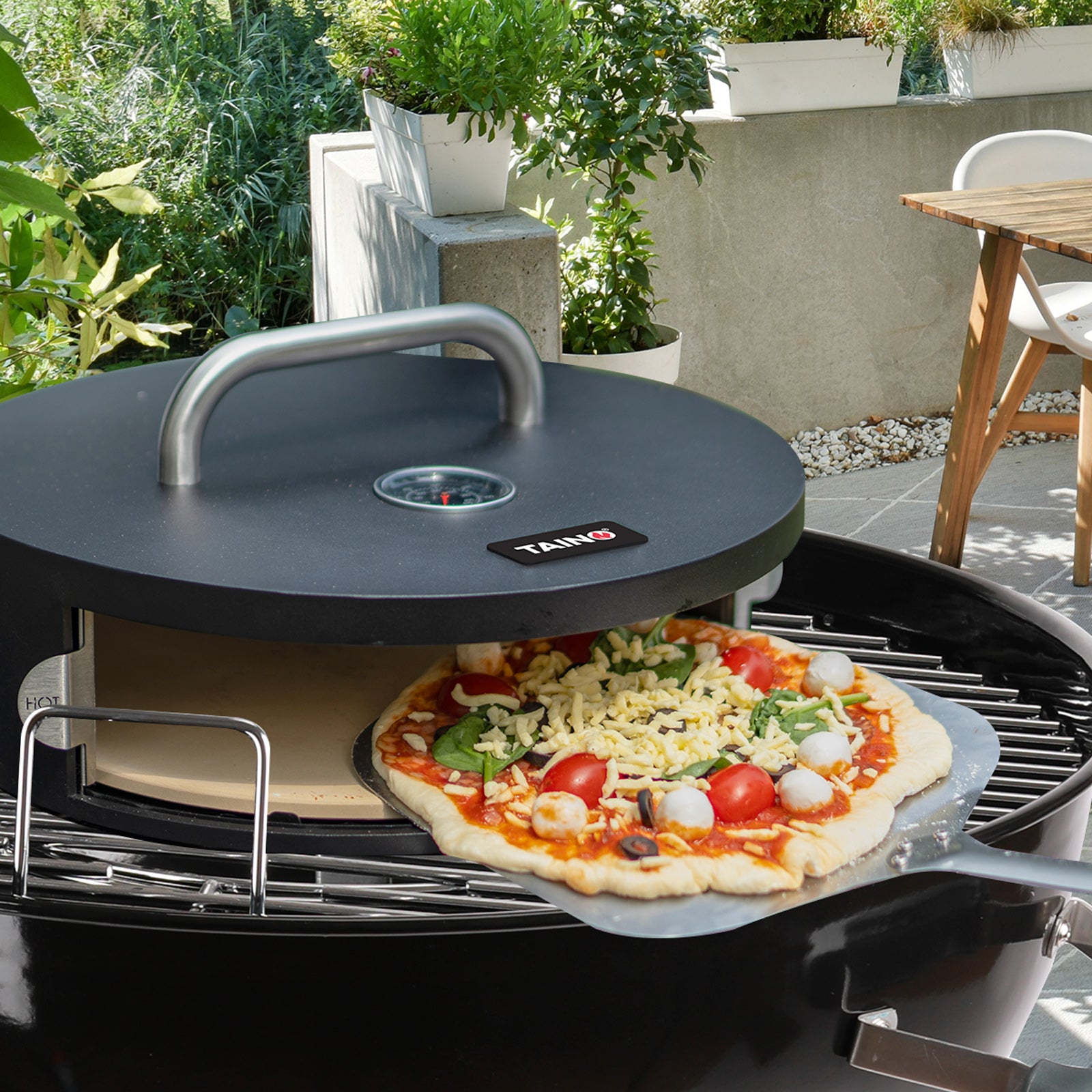 TAINO Pizzabox steht auf einem Grill - eine Pizza wird gerade reingeschoben