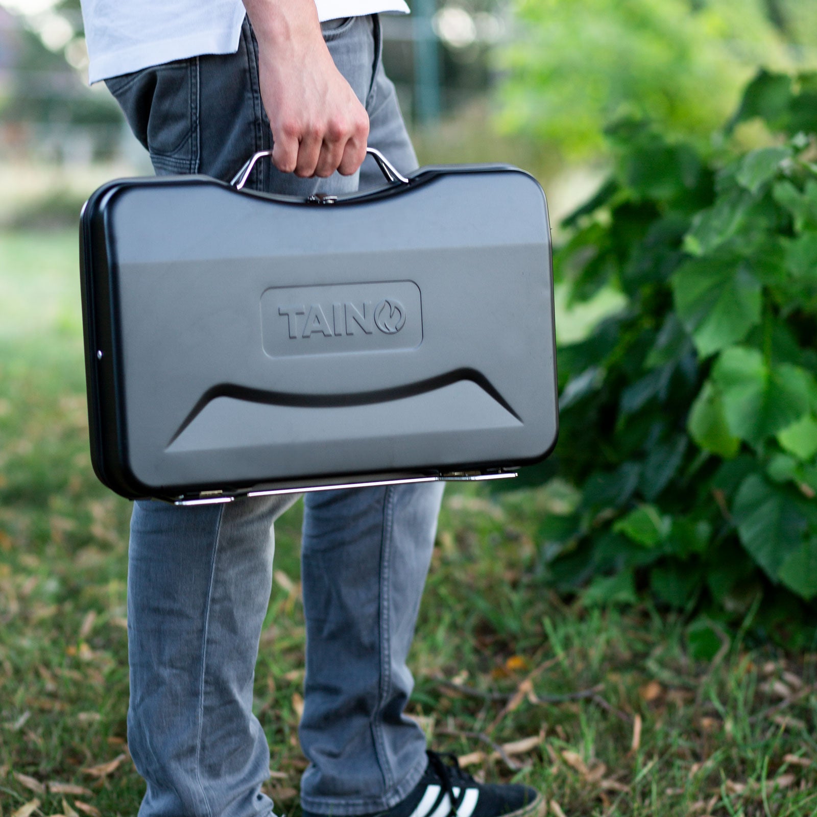 Koffergrill TAINO MOX schwarz wird von einer Person in der Hand gehalten